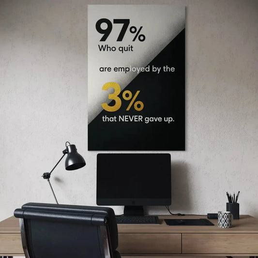 Angled room mockup of a vertical black-and-white canvas with gold 3% text stating “97% who quit are employed by the 3% that NEVER gave up,” displayed above a workspace.