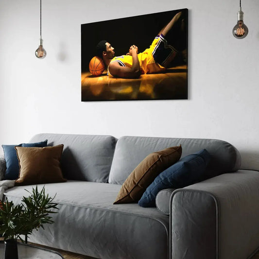 Framed wall art of a basketball player in a yellow jersey lying on the court with a ball under his head, moody lighting, living-room