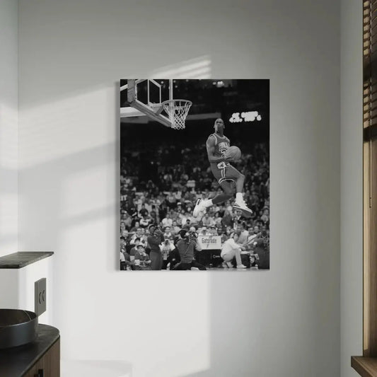 Black-and-white canvas print of Michael Jordan soaring for a slam dunk in front of a packed stadium, displayed as wall art in a modern interior.