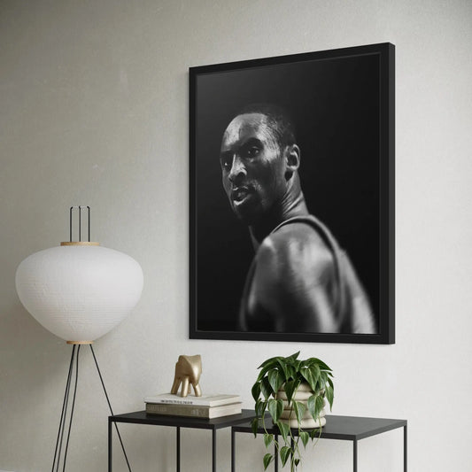 Framed black and white portrait of a man on a wall above a table with decor items.