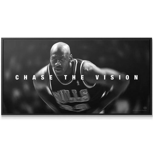 Black and white action shot of Michael Jordan - Chase The Vision, showing him leaning forward in his Bulls uniform.