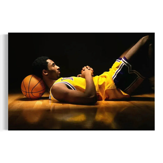 Poster artwork of a basketball player in a yellow uniform lying on the floor with a basketball under his head against a dark background.