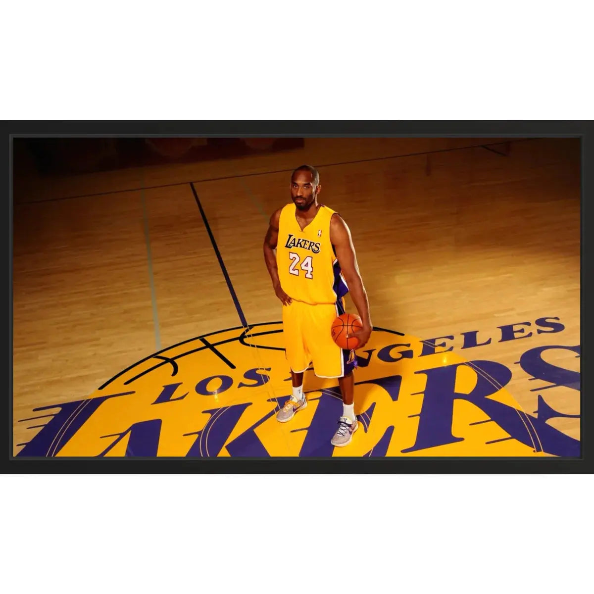 Framed print showing a basketball player in a yellow Los Angeles jersey #24 on the arena’s center-court logo, dramatic spotlight lighting.