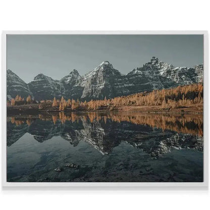 High-angle view highlighting the snowline and jagged peaks towering Above the Larches, contrasting with the warm foliage.