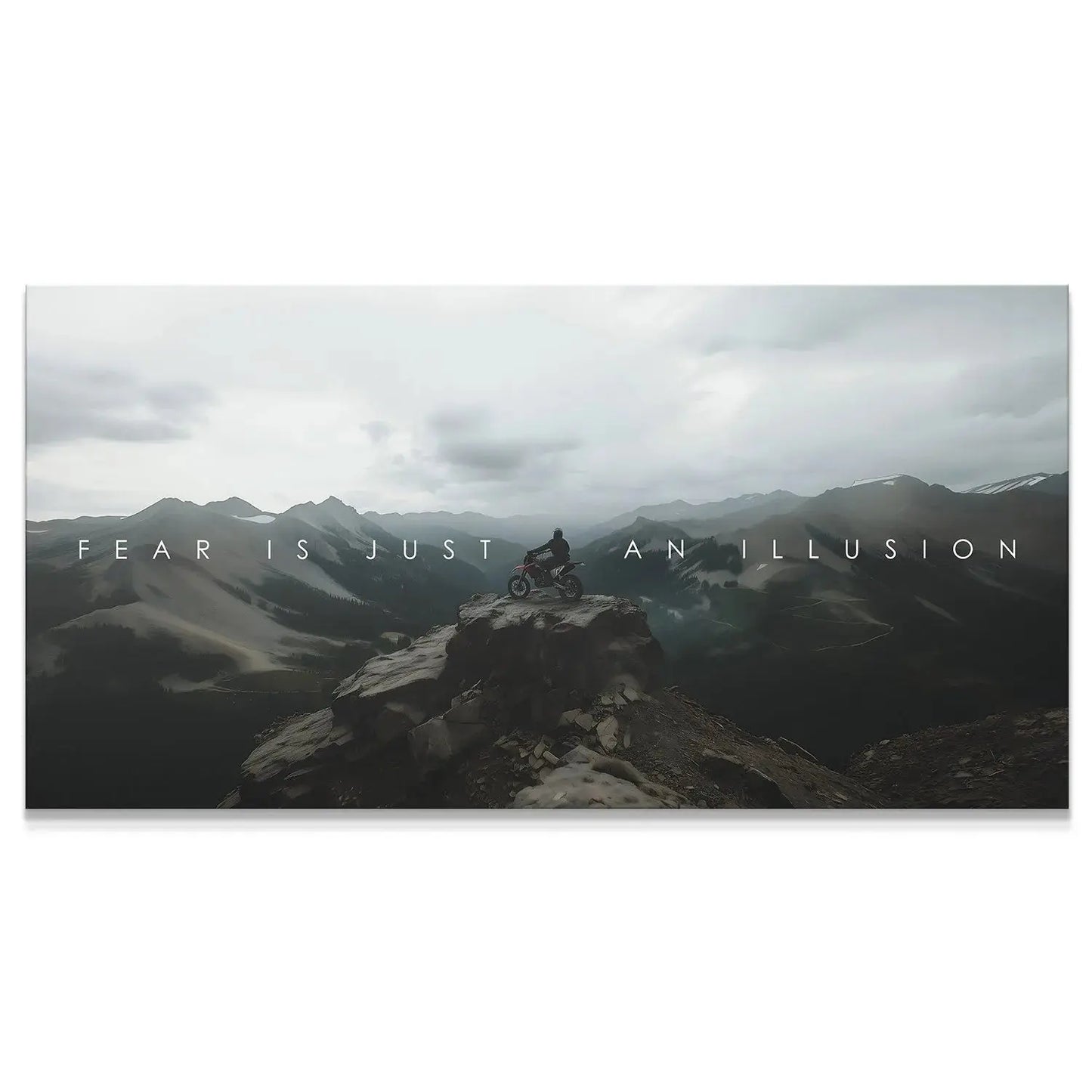 Wide panoramic view of the biker on the remote mountain peak, emphasizing the quote 'Action Sports - Fear Is Just An Illusion.'