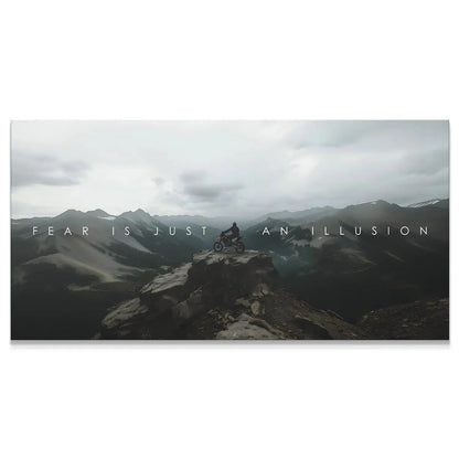 Wide panoramic view of the biker on the remote mountain peak, emphasizing the quote 'Action Sports - Fear Is Just An Illusion.'