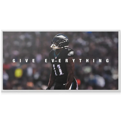 Lifestyle photo of the AJ Brown - Give Everything artwork hanging above a modern minimalist desk setup.