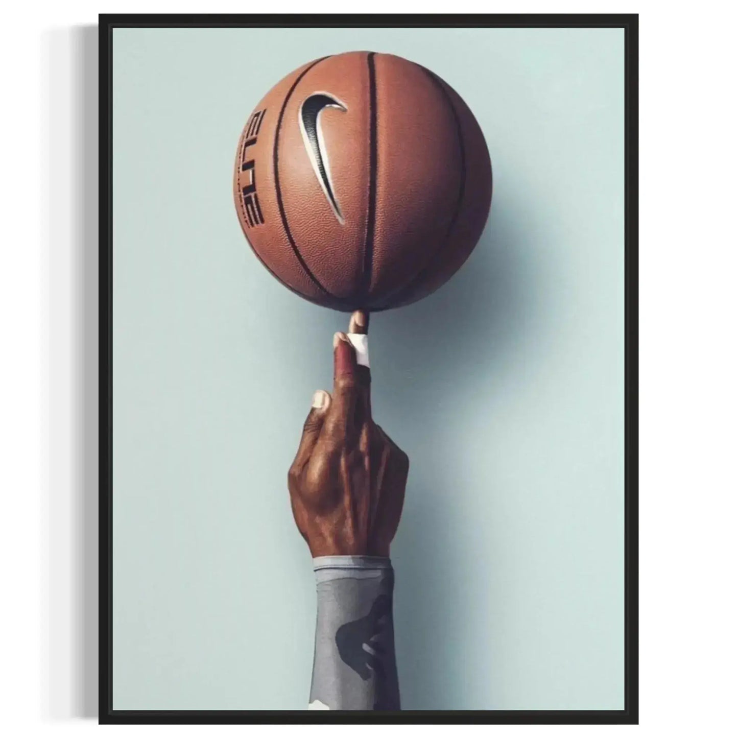 High contrast photography showing the rich brown tone of the ball and the dark arm against the light wall, defining the aesthetic of the Basketball Wall Art – Modern Sports Print for Dynamic Interiors.