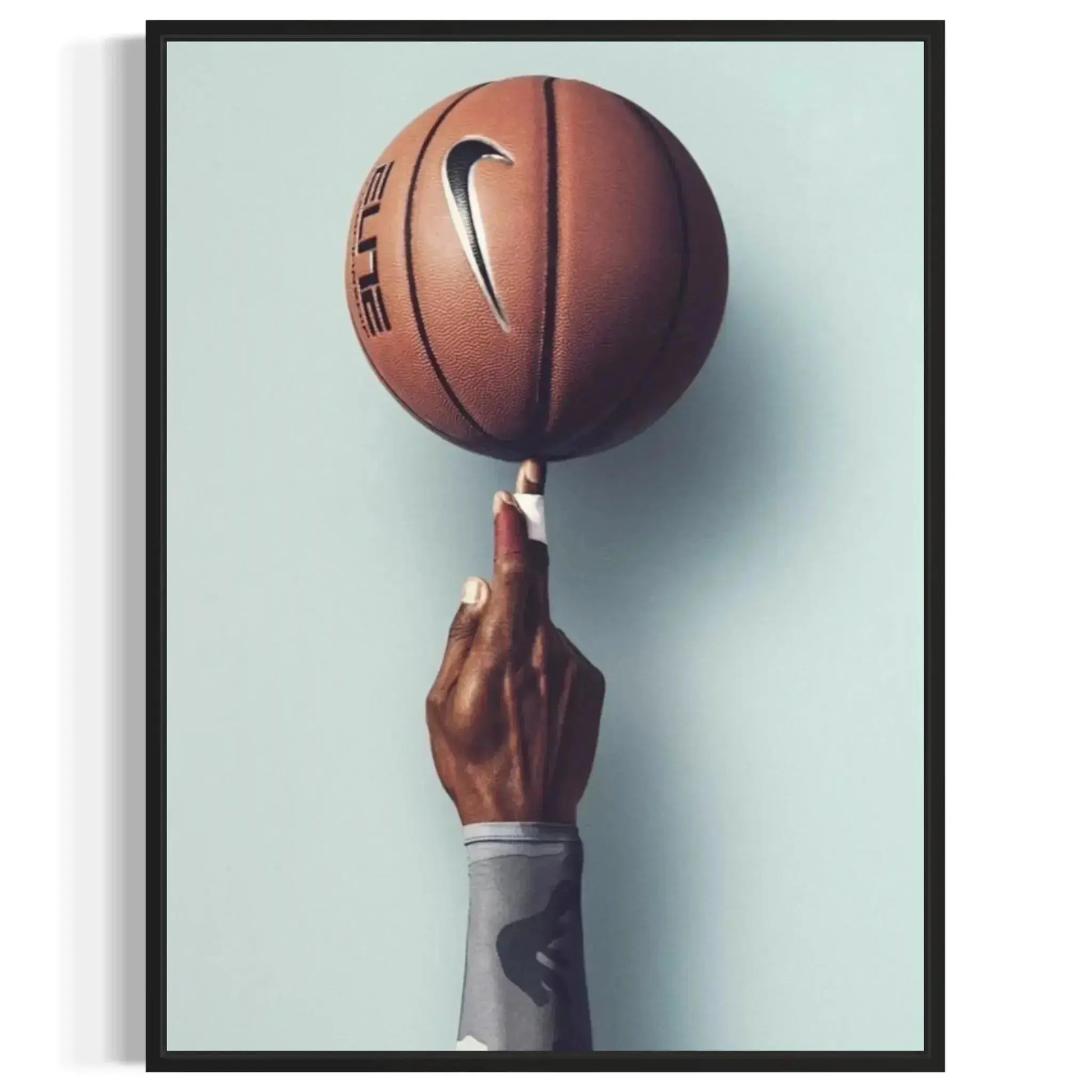 High contrast photography showing the rich brown tone of the ball and the dark arm against the light wall, defining the aesthetic of the Basketball Wall Art – Modern Sports Print for Dynamic Interiors.