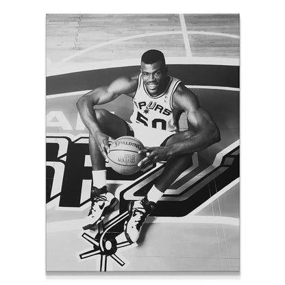 Black and white professional basketball portrait of David Robinson - #1 sitting mid-court, holding a Spalding ball.