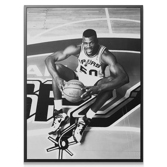 Close-up detailed view of NBA legend David Robinson - #1 smiling in his Spurs jersey, seated on the court.