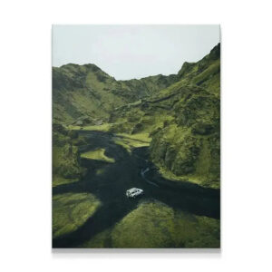 Wide aerial view of a white 4x4 driving on a black riverbed between steep, mossy green hills. Adventure Awaits.