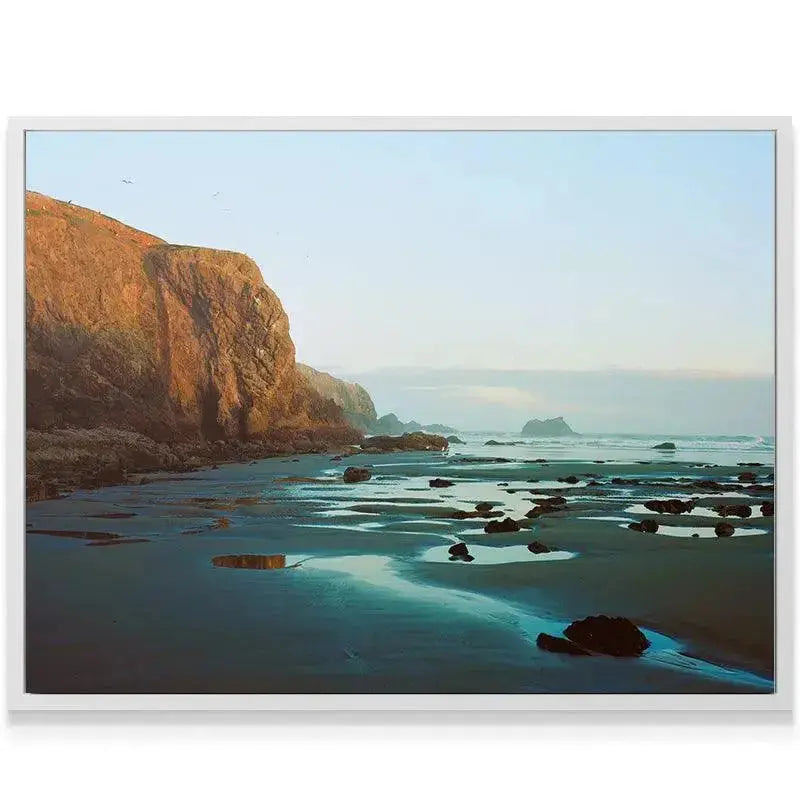 Reflective tide pools mirroring the soft blue sky on the Bandon beach landscape.