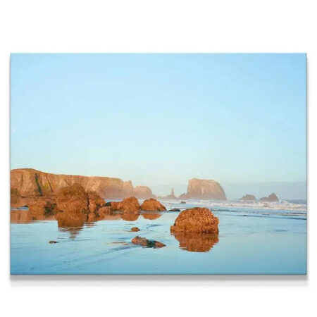 Wide shot of sea stacks reflecting on the wet sand, capturing the soft atmosphere of 'Bandon Blues'.