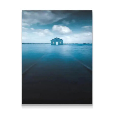 Wide shot of the iconic Blue Boat House centered on the vast, smooth blue water landscape.