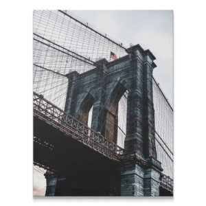 Low-angle view emphasizing the massive stone tower of the Brooklyn Bridge.