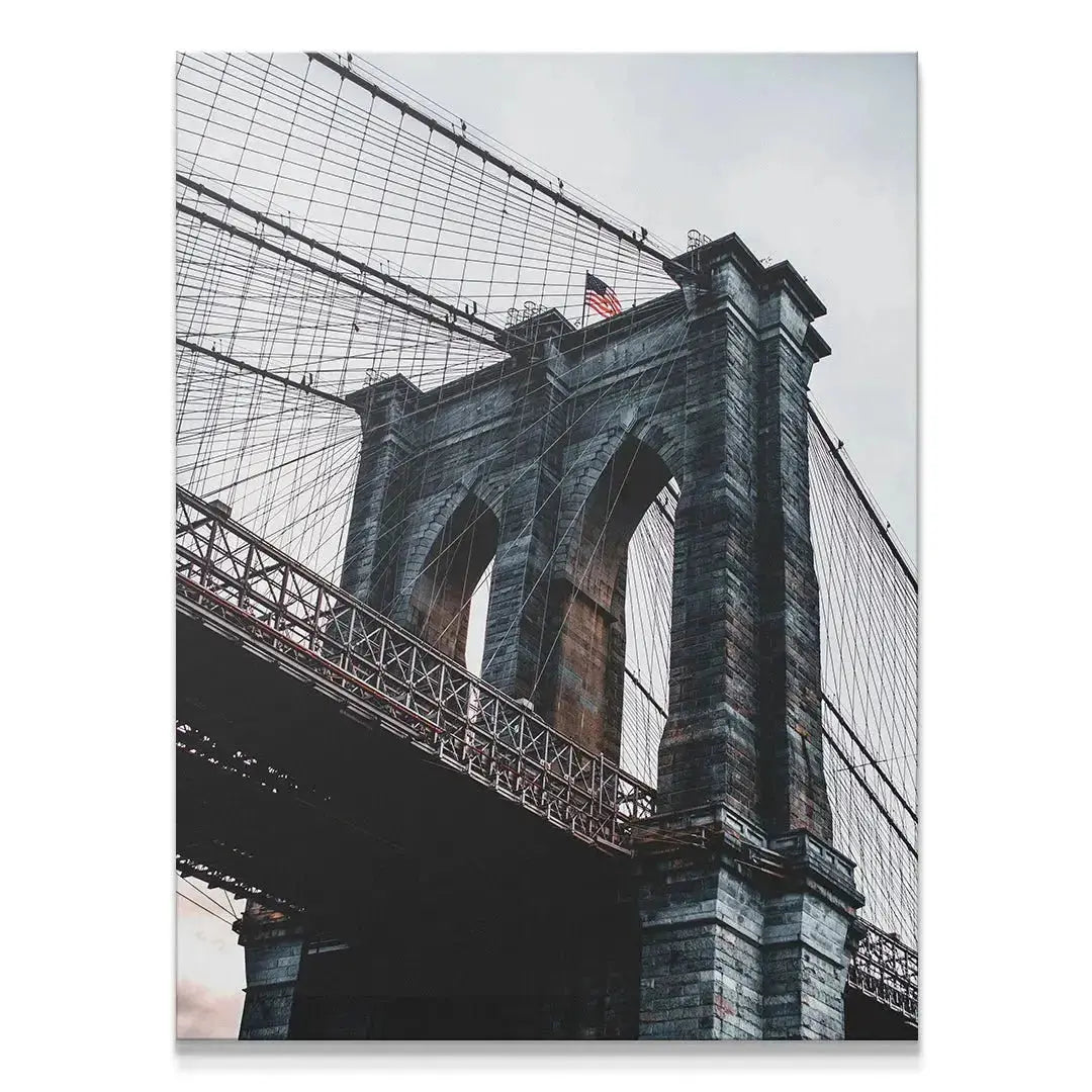 Low-angle view emphasizing the massive stone tower of the Brooklyn Bridge.