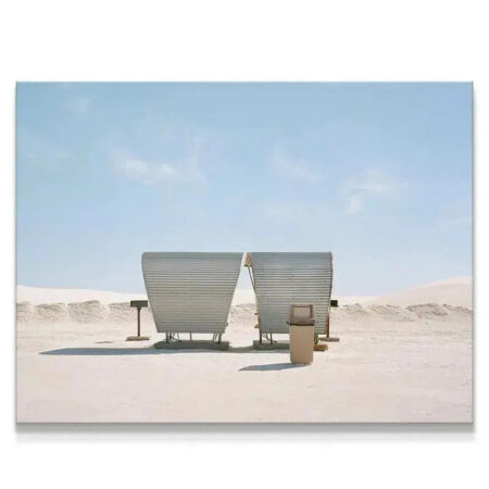 Wide-angle view of two identical corrugated metal shelters, nicknamed the 'Buds', standing in white desert sand.