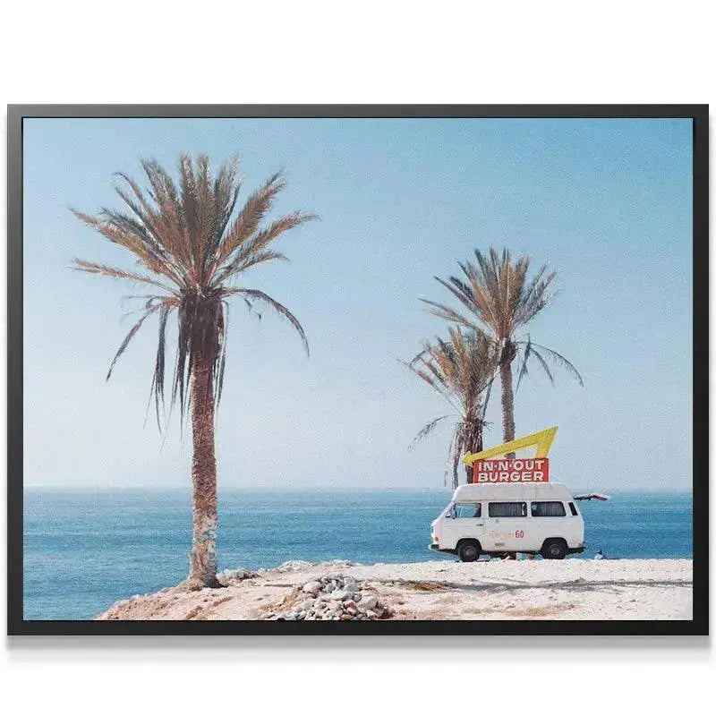 Wide shot featuring the tall palm trees framing the Burger Truck against the clear blue ocean and sky.