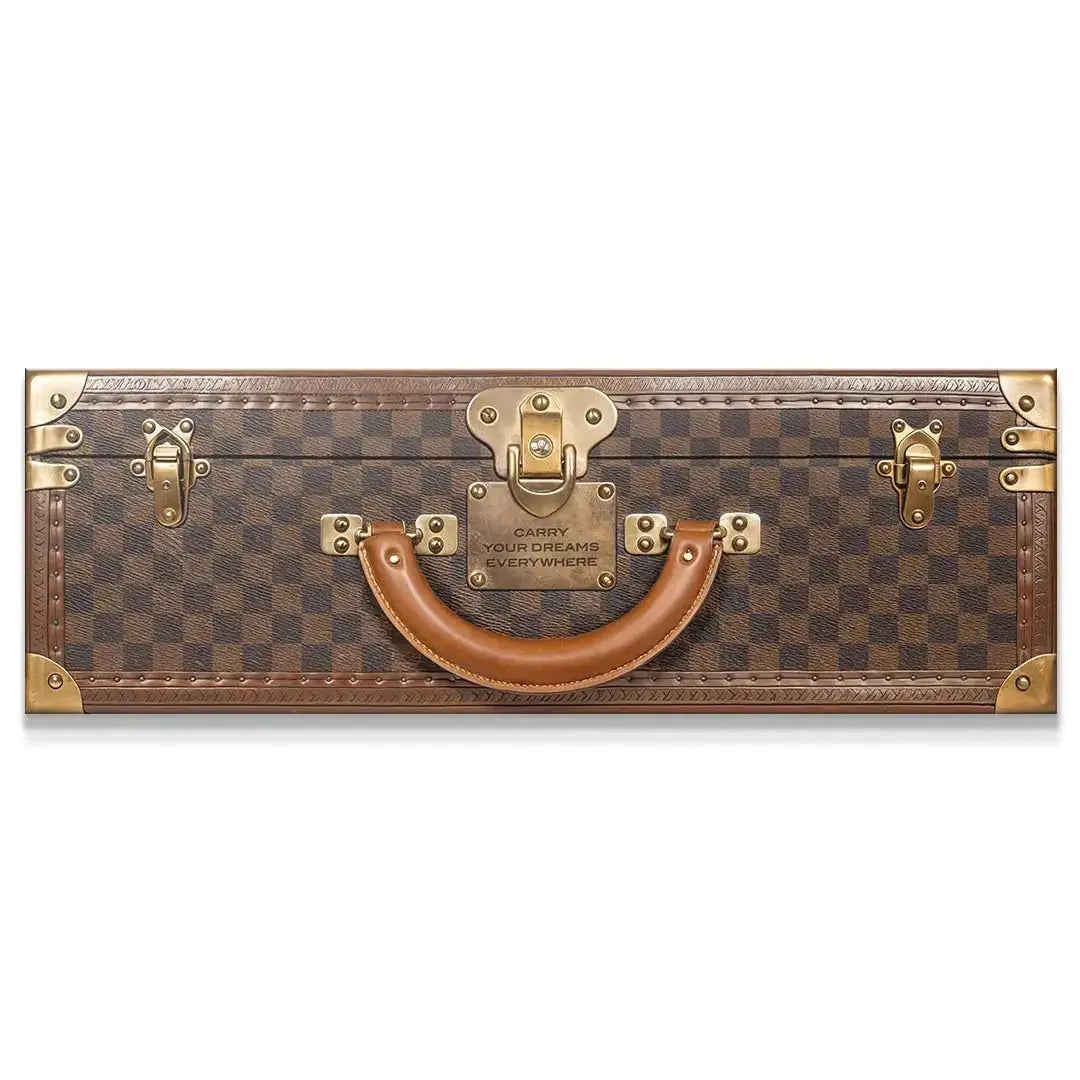 Close-up of the central brass plaque reading "Carry Your Dreams Everywhere" on the luxury checkered trunk.