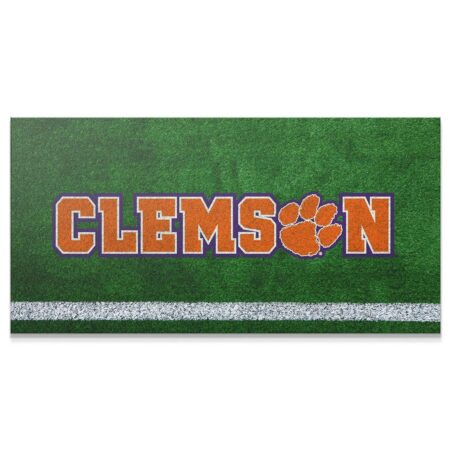 Close-up shot of the vibrant orange and purple text of the Clemson - Field Logo on artificial turf.