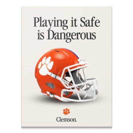 Full-frame studio shot of the orange Clemson helmet featured prominently in the Clemson - Playing It Safe V2 poster design.