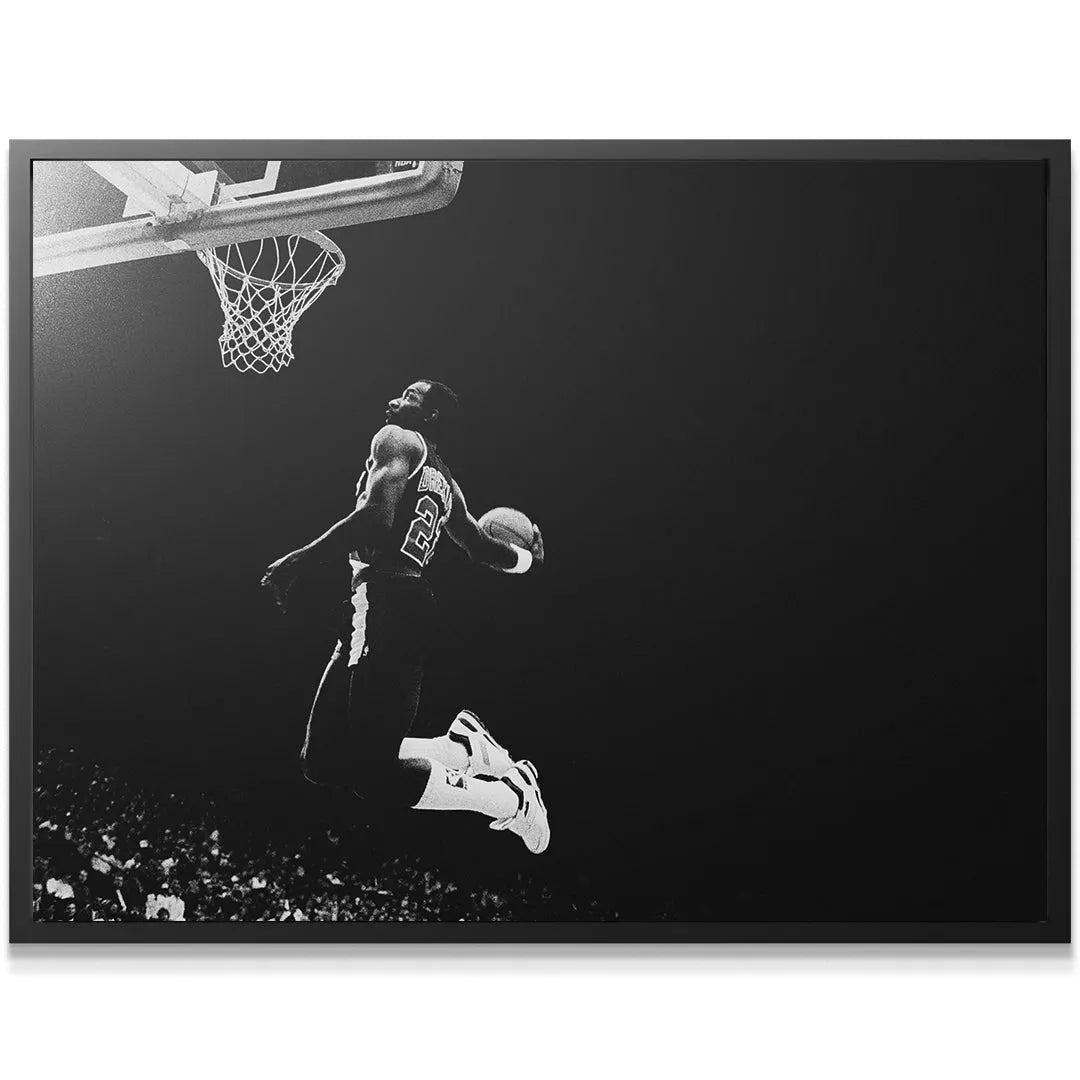 Low angle view capturing Clyde Drexler - #2 illuminated against a dark background, showing vertical leap.