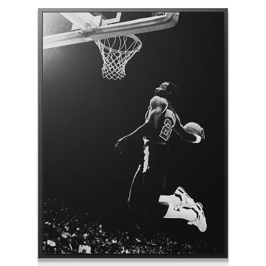 Angle showing Clyde Drexler #4 airborne above the rim, holding the basketball ready for a slam in this vintage photograph.