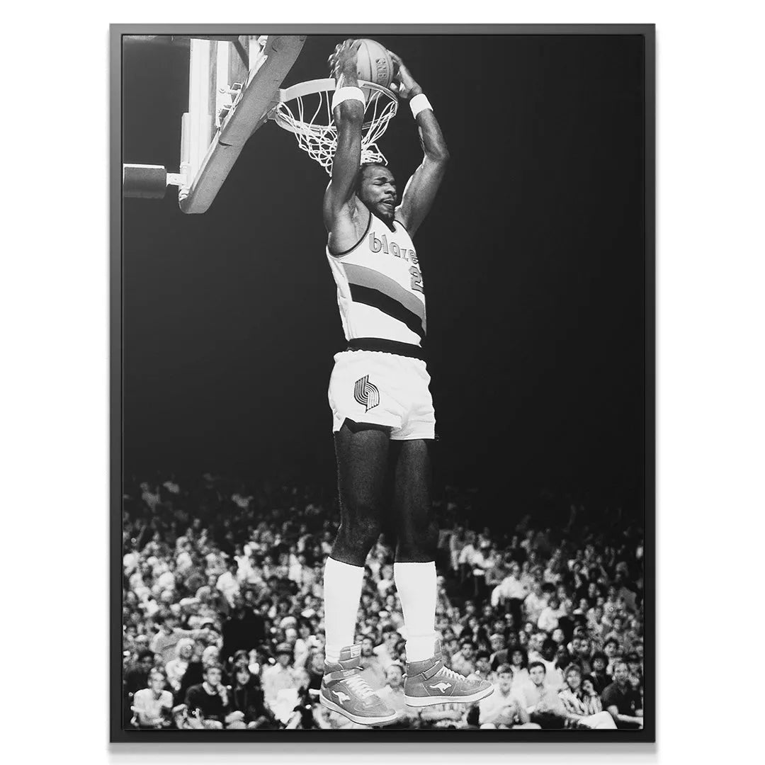 Close-up portrait of the intense expression on Clyde Drexler #5's face during his soaring jump.