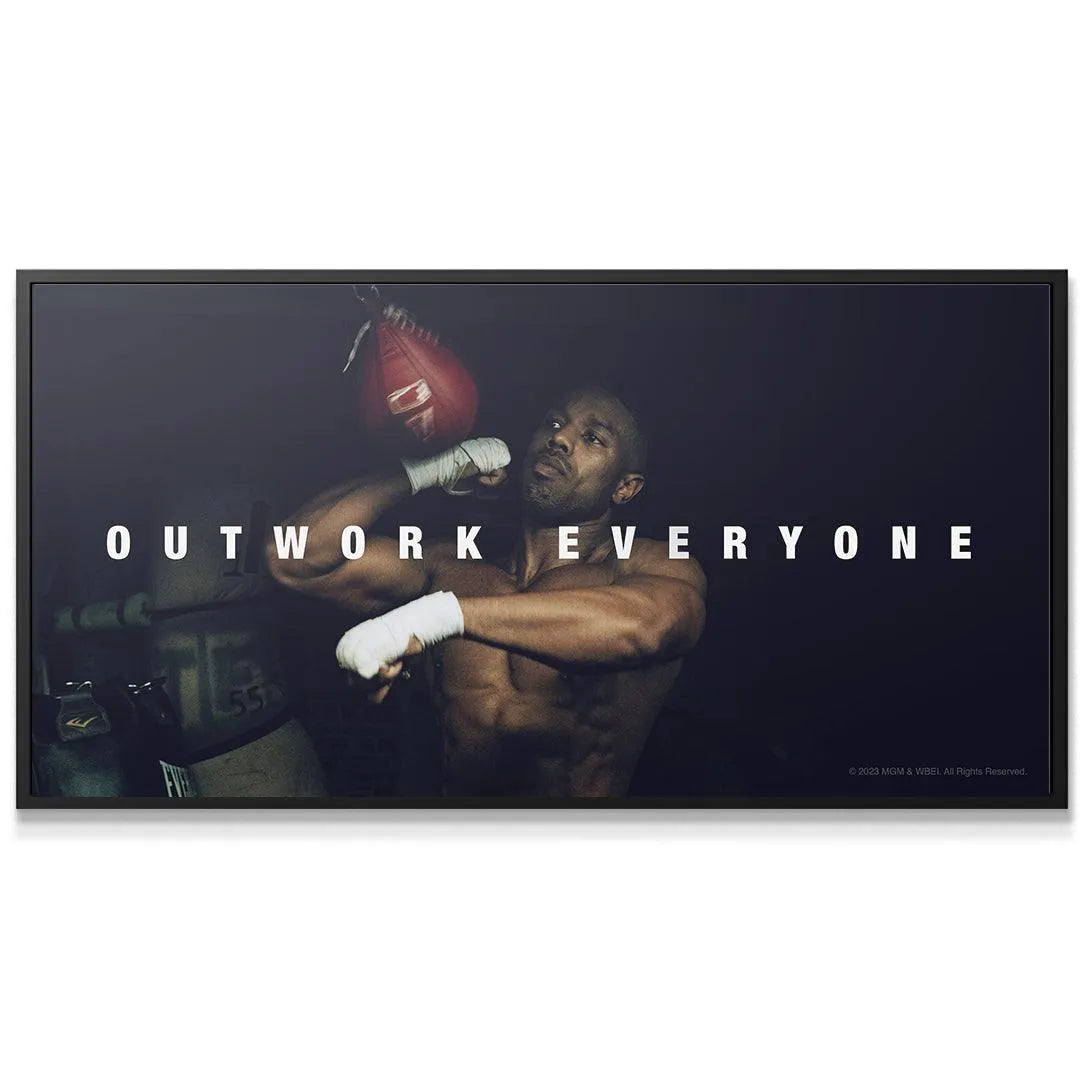 Wide-angle view of the motivational phrase 'Creed - Outwork Everyone' centered above Adonis in the boxing gym.