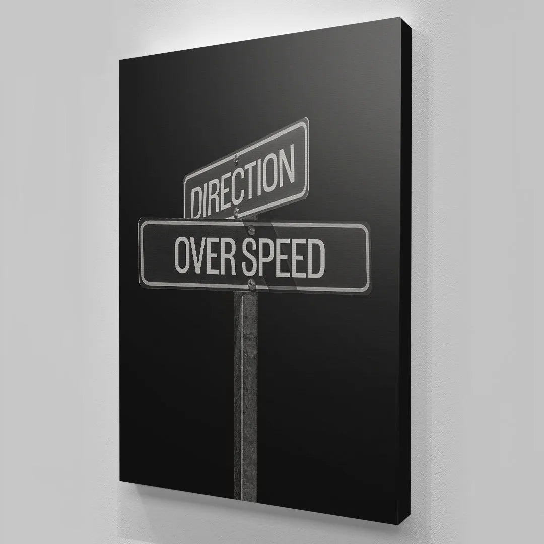 Detail of the bold, white typography on the black background of the two-panel Direction Over Speed Sign.