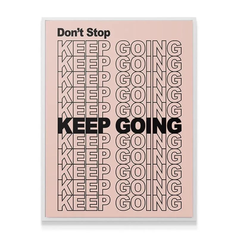 Lifestyle shot of the 'Don't Stop Keep Going' poster framed on a white office wall above a minimalist desk setup.