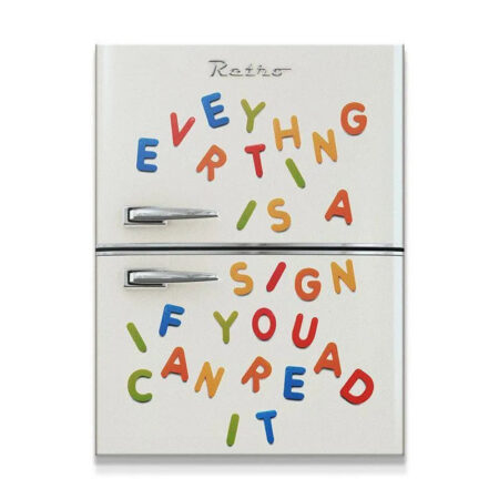 Close-up detail shot of the colorful magnetic letters spelling out 'Everything Is A Sign' on the fridge panel.