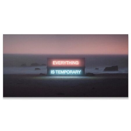 Wide shot of neon sign 'Everything Is Temporary' placed centrally on a dark, misty beach at dusk.