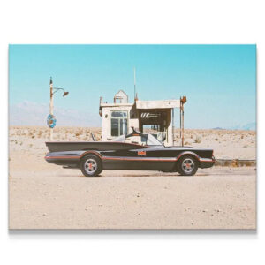 Full side profile of the iconic black car at the deserted 'Gas Stop' under a bright blue sky.