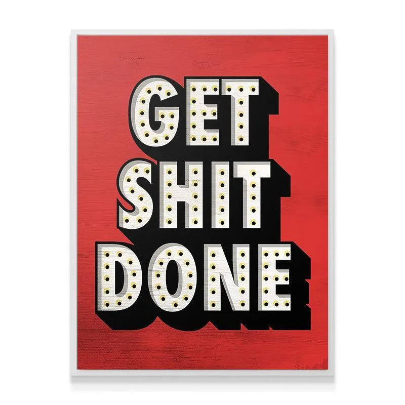 Angled shot of the motivational canvas sign Get Shit Done hanging in a modern workspace environment.