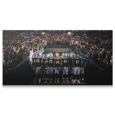 Wide shot of NFL players emerging from a dark tunnel framed by thousands of fan flashlights, embodying Give Everything (Football).