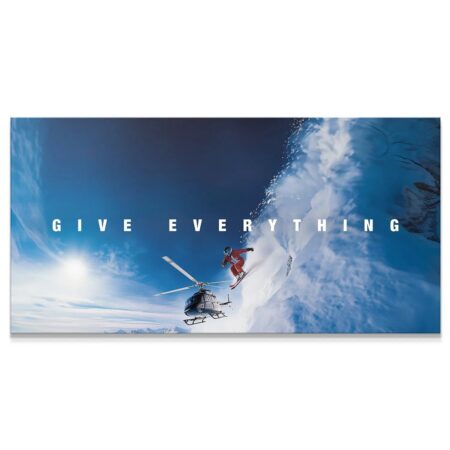 Wide-angle view of skier initiating a massive 'Give Everything - Jump' off a snowy cliff edge.