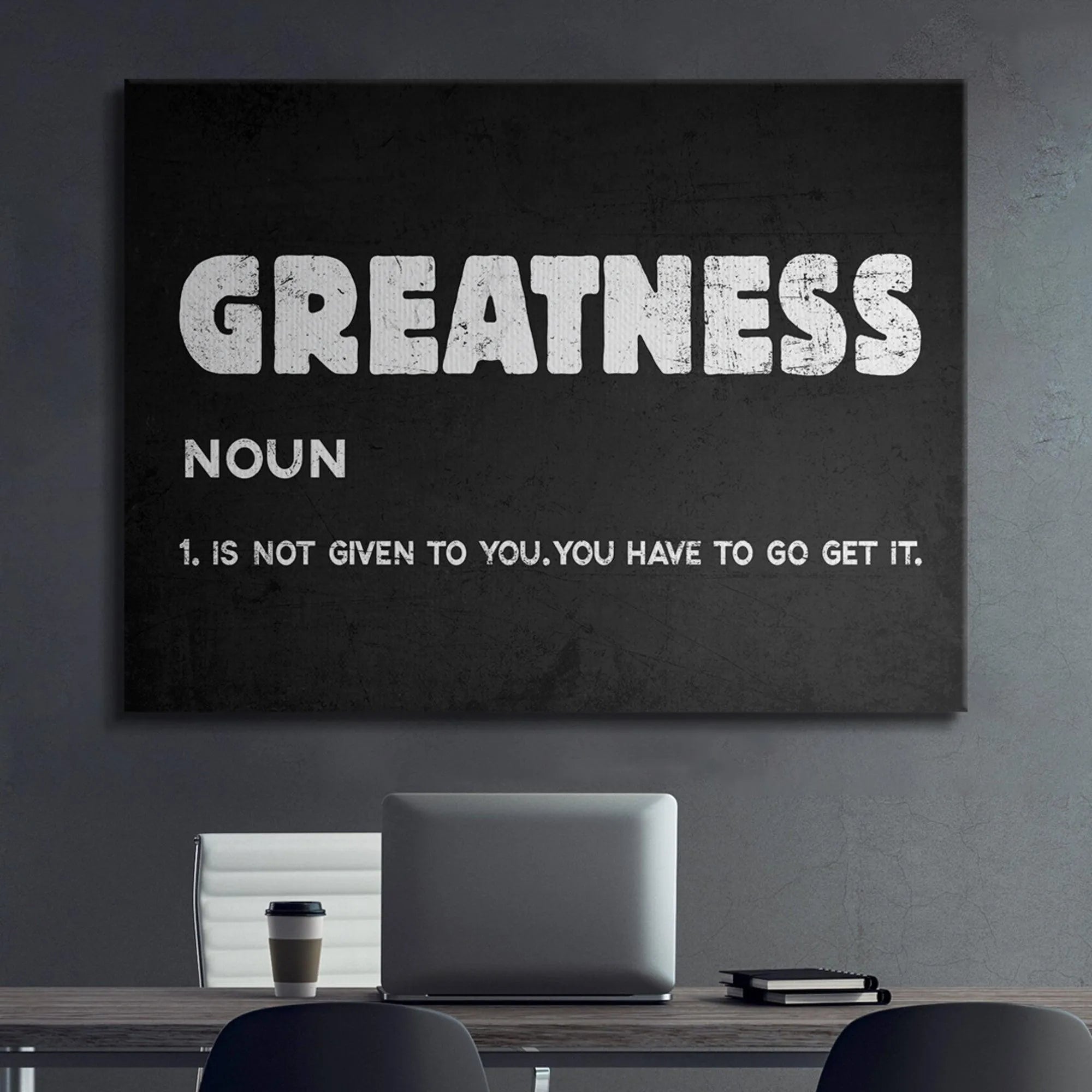 A lifestyle shot of the Greatness definition print mounted above a weight bench in a gym.