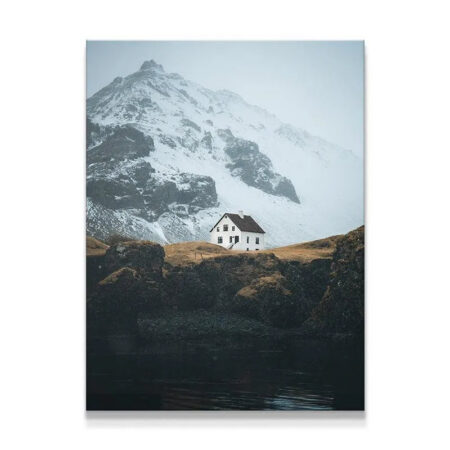 Remote white Home nestled on a rugged cliffside overlooking dark water.