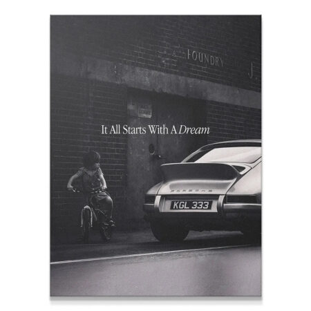 Monochrome art print showing a child on a bicycle near a classic Porsche; It All Starts With A Dream quote visible on the brick wall.