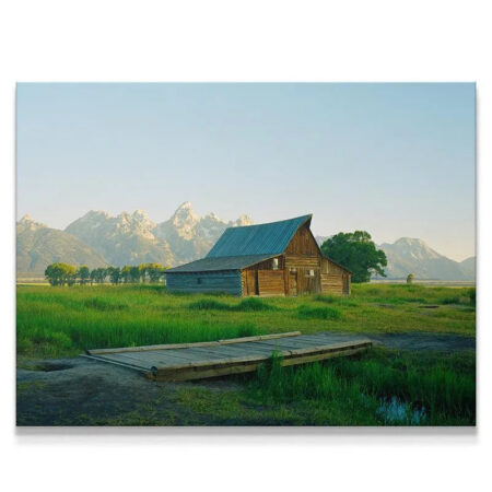 Wide view of the iconic Jackson Greens landscape featuring the historic barn, lush green fields, and Teton range peaks.
