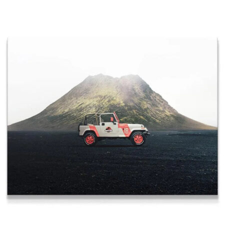 Wide shot of the iconic Jurassic Jeep parked on black volcanic ash against a misty mountain.