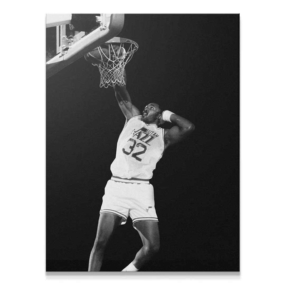 Close-up view of Karl Malone - #2 mid-dunk, focusing on his intense expression and muscular arm holding the rim.