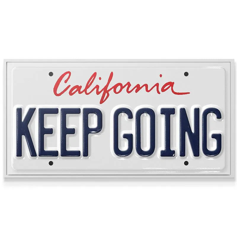 Angled shot highlighting the raised texture and gloss finish of the 'Keep Going - CA' metal sign.