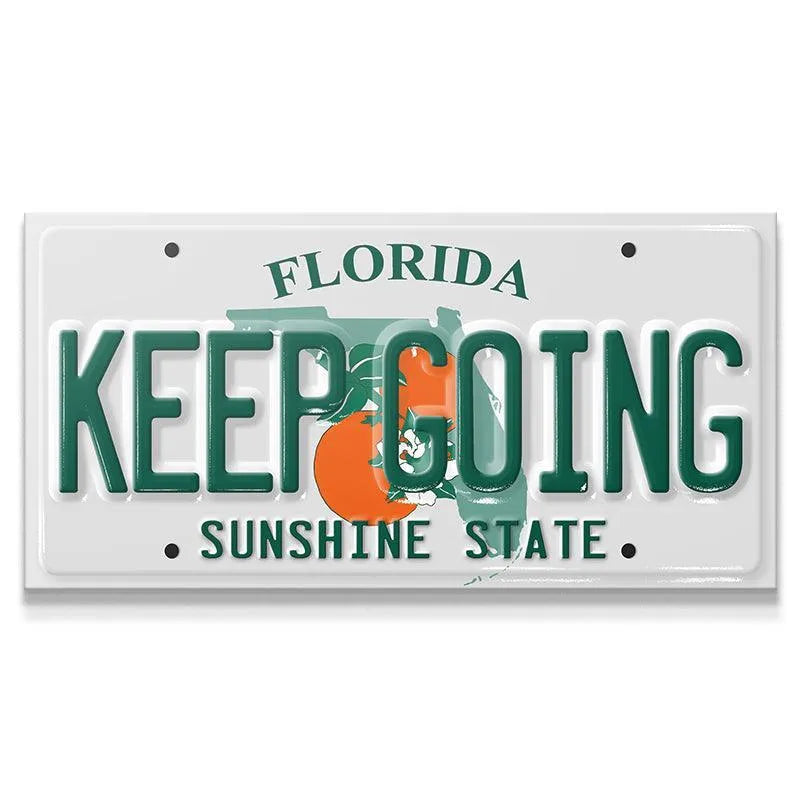 Front view of the white, green, and orange Keep Going - FL novelty license plate sign.