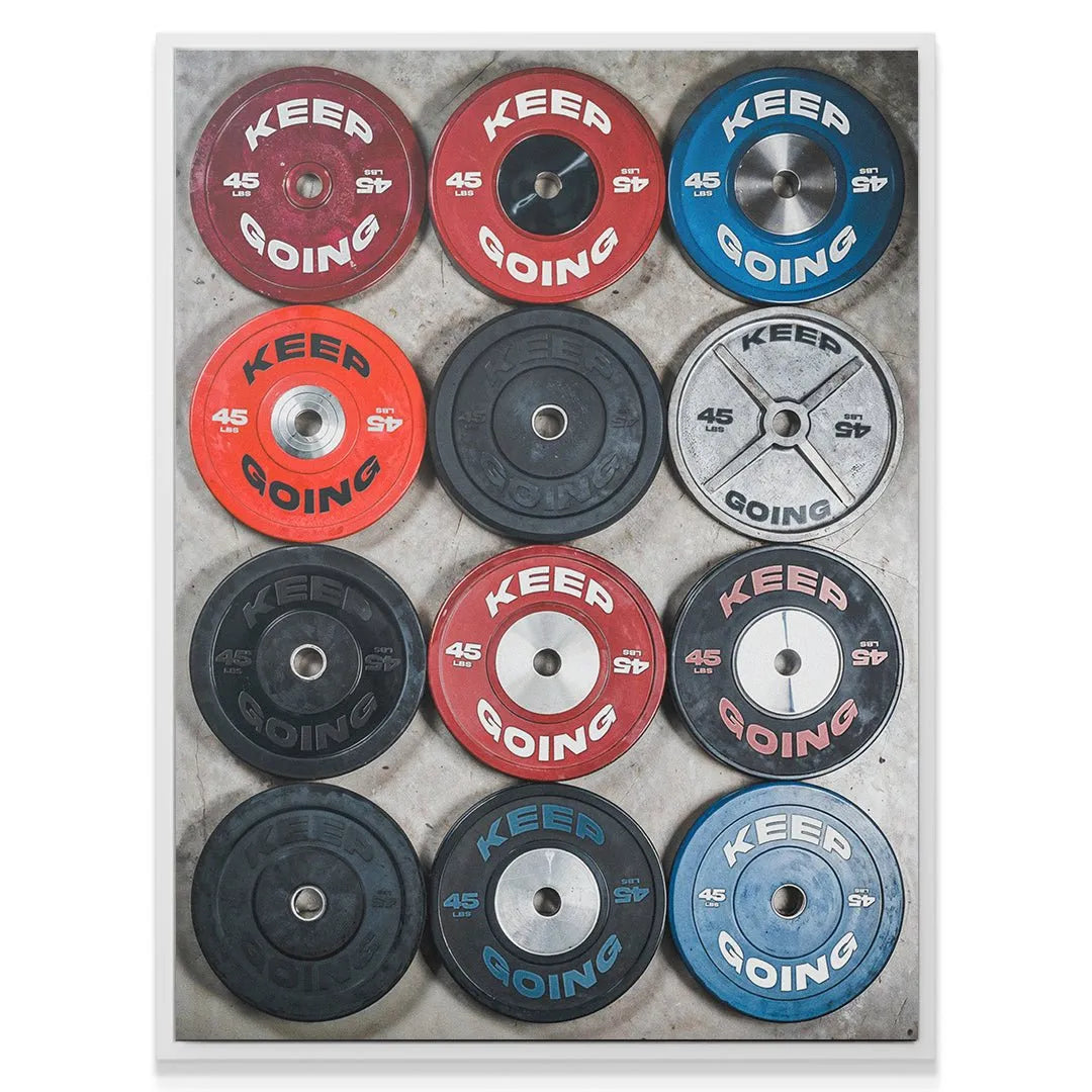 Wide shot showing twelve distinct, stacked 45 lb 'Keep Going Plates' on concrete.