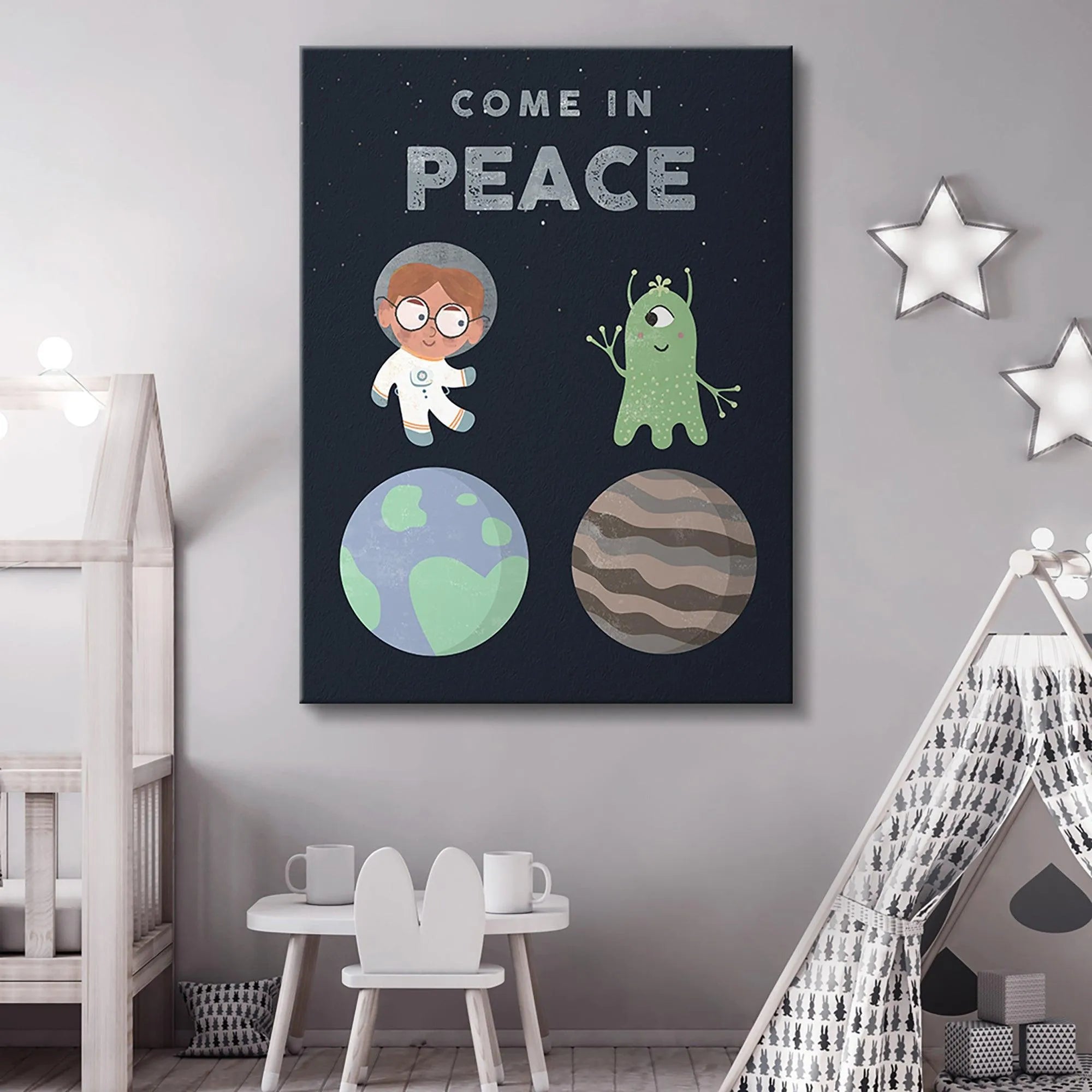Lifestyle shot of the 'Kids Come In Peace' art hanging framed above a crib in a modern, neutral-toned nursery setting.