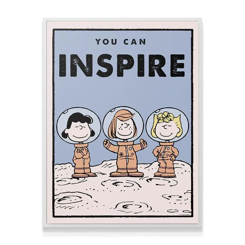 A lifestyle shot showing the framed 'Kids PEANUTS - You Can Inspire' art hanging in a brightly lit child's bedroom above a wooden desk.