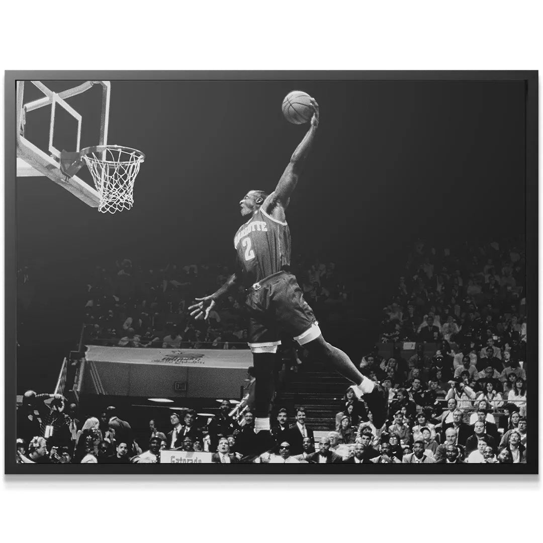 Wide-angle, low-key black and white photograph capturing Larry Johnson - #2 soaring toward the hoop over the crowd.